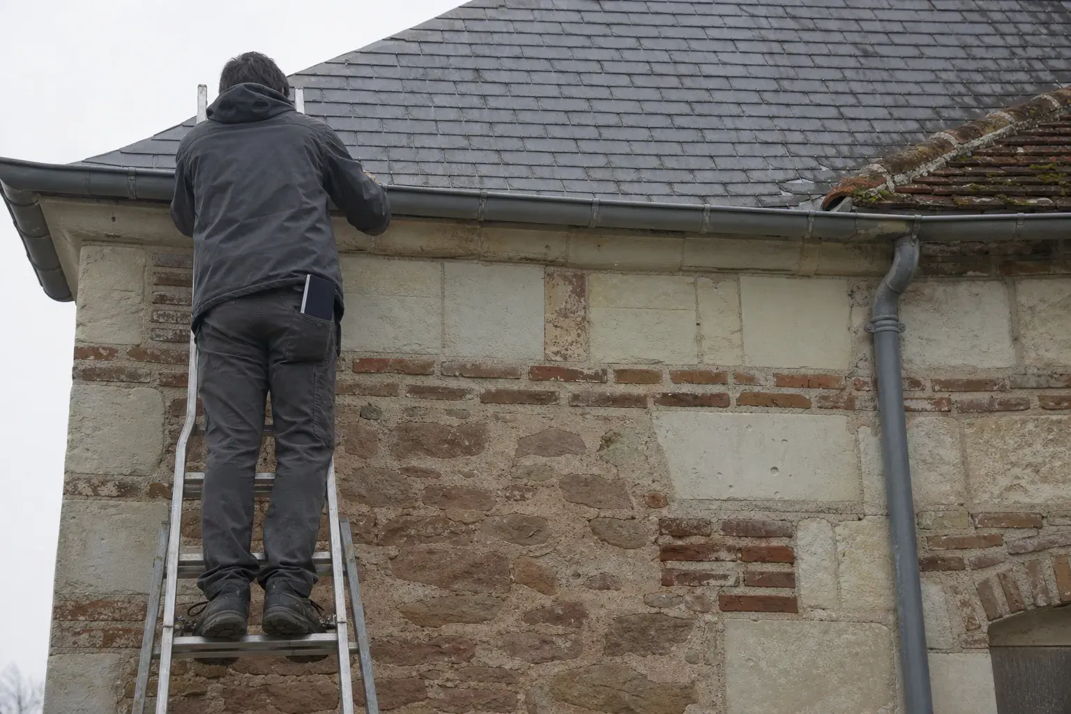 Contrôle depuis une échelle à hauteur de gouttière, examen des premiers rangs d’un versant d’ardoise